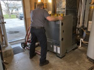 Setting a new furnace in place during installation by 7th Degree Heating and Air